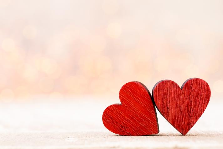 Two red wooden hearts leaning against each other.